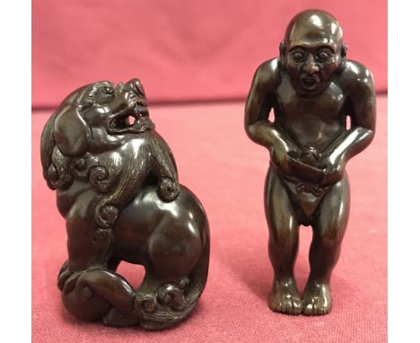 A Japanese dark wood erotic netsuke of an oriental gentleman. Together with a Japanese dark wood netsuke of a lion dog. Both 