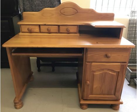 A modern pine desk with curved upper shelf and 3 small drawers. Lower pedestal has single drawer and single door cupboard wit