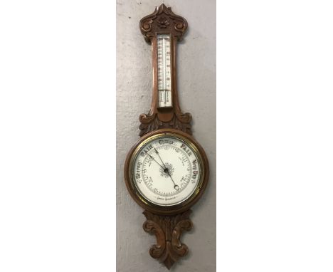A vintage wall hanging Aneroid barometer, with carved detail and integral thermometer. Glass casing to thermometer is loose. 