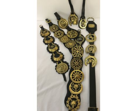 A collection of vintage horse brasses mounted on leather straps.  