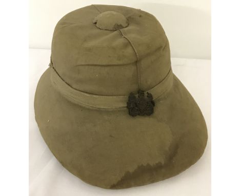 A vintage military khaki pith helmet with leather interior &amp; strap and cap badge to front.  