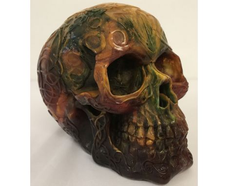 A large carved multi coloured resin skull figurine decorated with Pagan style symbols.  Approx. 14cm tall.