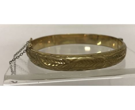 A vintage 9ct rolled gold, hinged bangle with half engraved decoration and safety chain. Marked to inside of bangle 'B Ltd.50