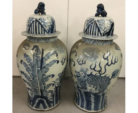 A pair of large floor standing, blue and white ceramic, lidded temple jars. With hand painted dragon detail and foo dog finia