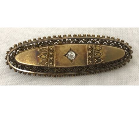 A vintage decorative oval shaped brooch set with a single round cut diamond. Tests as 9ct. Pierced work and bead design to su