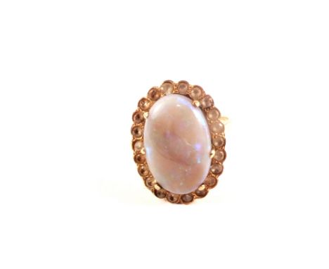 A gold ring set with large opal stone with white stone border, size M