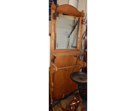 A 20th century pine hallstand, with an arched cornice above a rectangular mirror plate flanked by wrought iron pegs above a s