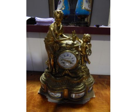 A 19th Century French gilt metal mantel clock cast with a maiden washing with angel attendant around a circular white enamel 