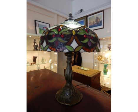 A Tiffany style table lamp, the stained glass shade with foliate design on a cast foliate base, H. 44cm
