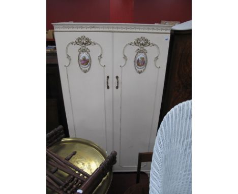 A Vintage White French Style Two Door Wardrobe, cornice with swag decoration, doors with applied decoration and oval shaped p