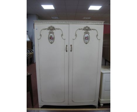 A Vintage White French Style Two Door Wardrobe, cornice with swag decoration doors, with applied decoration and oval shaped p