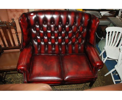 A modern red Leather button and wing back two seater hotel reception Sofa, having scroll arms and moulded square legs.
