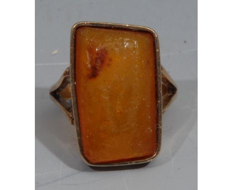 Natural History - an unmarked gold ring, set with an amber specimen containing an insect, the table 2.5cm x 1.5cm, 8g gross