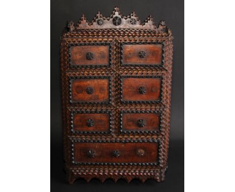 A late 19th century tramp art wall cabinet, shaped cresting above a door applied with six faux drawer fronts, the base with a