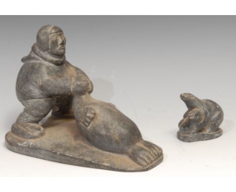 An Inuit soapstone carving, of a hunter and a seal, 21cm long, label for Canadian Inuit Art, mid 20th century; another (2) 