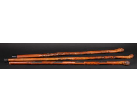 A Japanese bamboo walking stick or cane, carved with figures in a landscape, 81cm long, Meiji period; others, similar (3) 