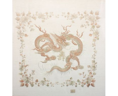 A Chinese needlework picture, worked in two-tone threads with a ferocious dragon, within a flowering border, centred by a cha