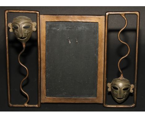 An Art Deco period painted metal easel photograph frame, the rectangular aperture flanked by African tribal masks, 20cm x 26c