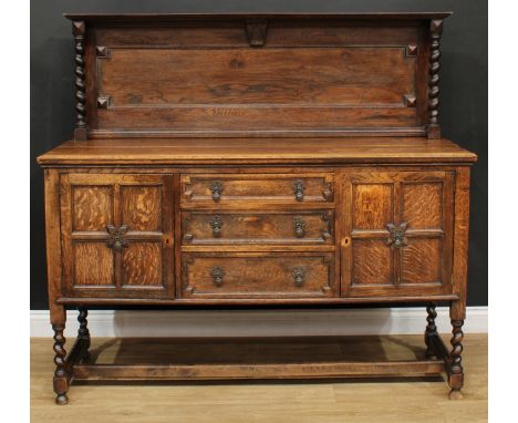 A Jacobean Revival oak sideboard, outswept cornice above a reentrant panel, the projecting base with drawers and cupboard, sp