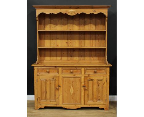 A farmhouse pine dresser, moulded cornice above a shaped apron and a pair of plate racks, the projecting base with three shor