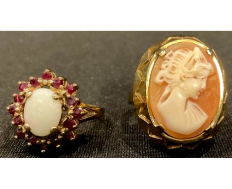 A 9ct gold ring, set with a carved shell cameo, size O, 6.3g; a 9ct gold polished opal ring, surrounded by a cluster of ruby 