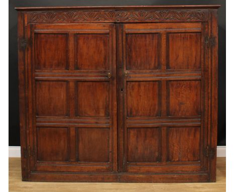 An oak housekeeper's cupboard, rectangular top above frieze carved with leafy lunettes, above a pair of panel doors, each enc