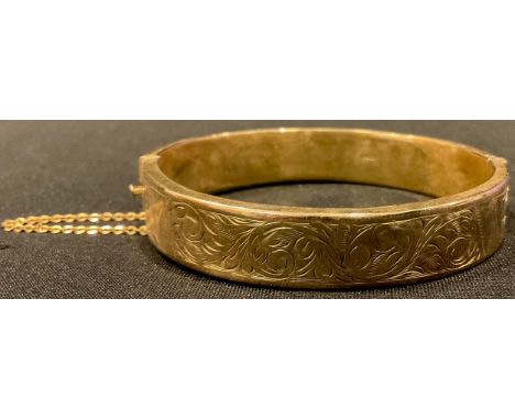 A 9ct gold hinged bangle, chased and engraved with scrolls, safety chain, marked 375, 15.3g 