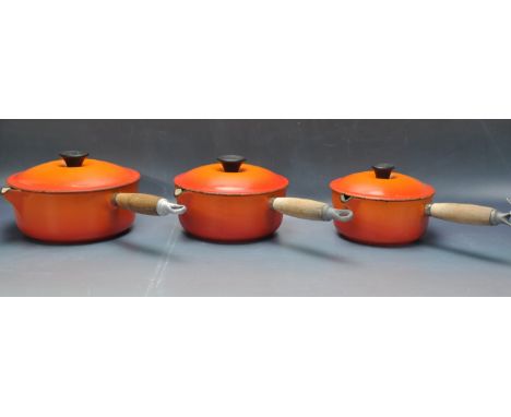 A collection of vintage 20th century cast iron enamel Le Creuset pots of graduating sizes having a wooden handle with makers 