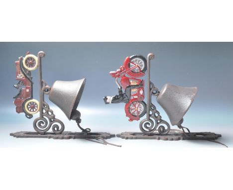 Two vintage style cast iron bells of automobile interest having scrolled supports with a polychrome motorcyclist / motorcar i