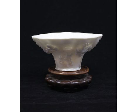 A Qing Dynasty. Dehua Blanc de Chine porcelain Libation Cup shaped as a Rhinoceros horn, the exterior sprig moulded with a de