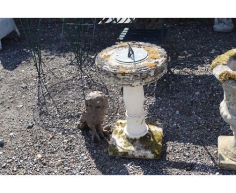 A sundial on concrete stand together with an owl ornament