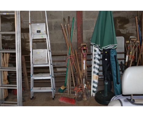 A quantity of long and short handled gardening tools to include brooms, forks, pickaxe heads etc.