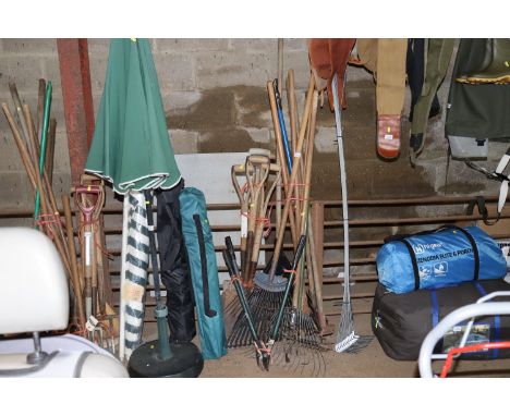A quantity of long and short handled garden tools to include rakes, spades, hoes etc.