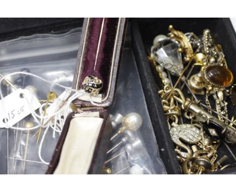 A BLACK LEATHER BOX containing 19th century gold stick pins including a Momento Mori enamel example and a selection of brooch