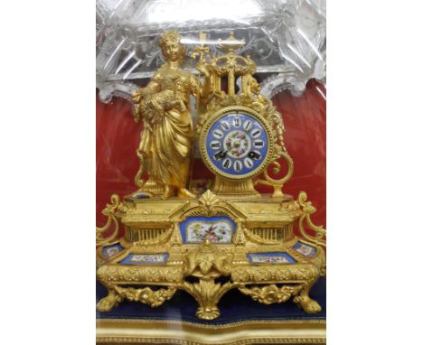A 19TH CENTURY FRENCH GILT CLOCK with hand painted porcelain panels inset to the base, the enamel face painted with Roman num