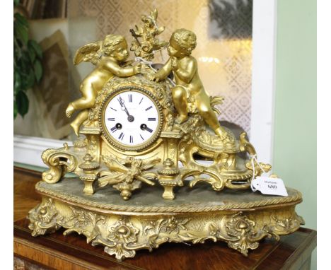 A FRENCH GILT METAL MANTLE CLOCK decorated with Cherubs and foliage on scrolling acanthus velvet lined base with Roman numera