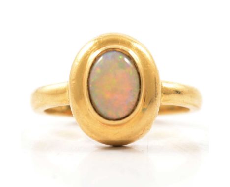 An opal dress ring, the oval cabochon cut stone 7.2x5.4mm, rubbed over set in an 18 carat all yellow gold mount ring size L, 