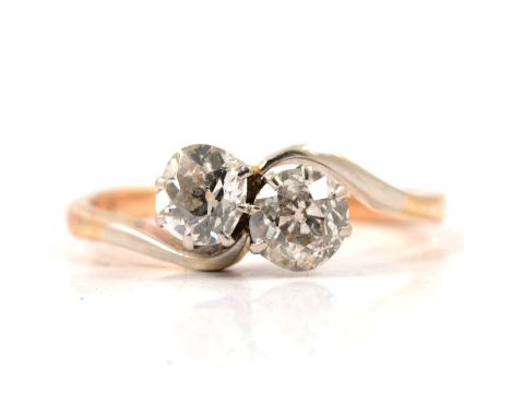 A diamond two stone crossover ring, the old brilliant cut stones claw set in a yellow and white metal mount ring size O, shan