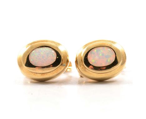 A pair of opal earrings, the oval cabochon cut stones, 7.3x5.4mm, collet set in yellow metal claw back mounts with plain poli