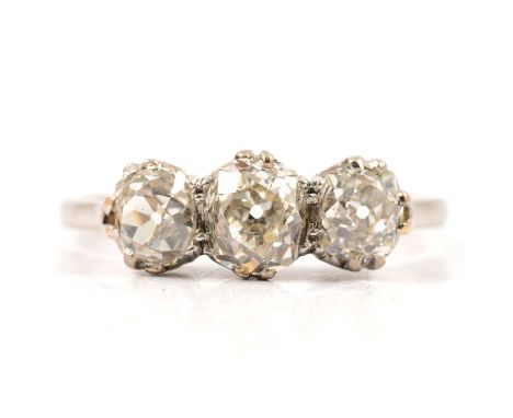 A diamond three stone ring, the old brilliant cut stones claw set in an all white metal traditional three stone mount ring si