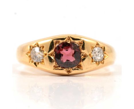 A synthetic red stone and diamond three stone ring, the old cut diamonds and red stone star gypsy set in an 18 carat yellow g