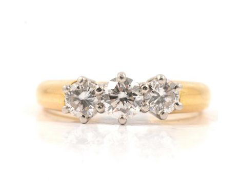 A diamond three stone ring, the brilliant cut stones claw set in an 18 carat yellow and white gold traditional three stone mo