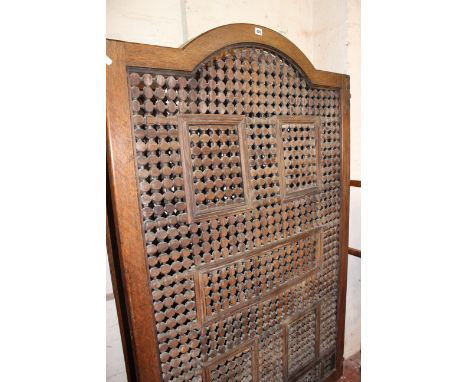A South East Asian oak arched framed folding screen with pierced decoration each panel 173cm high111cm wide 