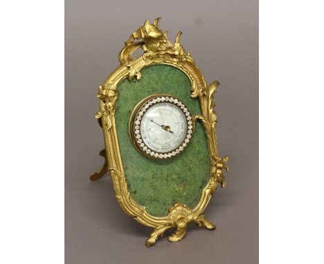 A FRENCH ANEROID BAROMETER, the 2 1/4" enamelled dial marked Toricelli, in a scrolling gilt frame with easel stand, height 22