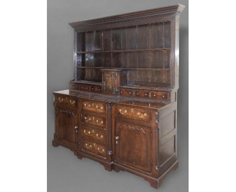 AN 18TH CENTURY OAK DRESSER, the top with three shelf plate rack above an arrangement of six small drawers flanking a small s