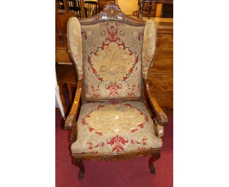 An early 20th century Italian floral carved walnut wing back open scroll armchair, having needlework tapestry upholstery (dam