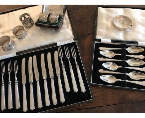 Two cases of hallmarked silver flatware, (a dessert set and grapefruit set), five silver napkin rings and a silver hinged ban