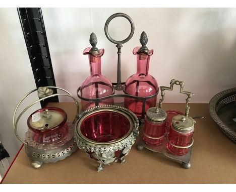 An Edwardian decanter stand with two cranberry glass decanters having silver plated cranberry pineapple stoppers, fitted in s