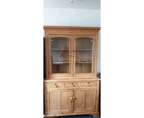 A Victorian pine bookcase on chest, circa 1870, moulded cornice above a pair of glazed doors enclosing three adjustable shelv