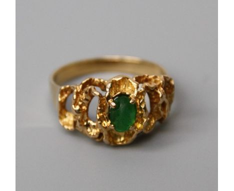 A single stone emerald ring, the oval emerald in pierced undulating mount. 5.7g, stone scuffed and pitted&nbsp;